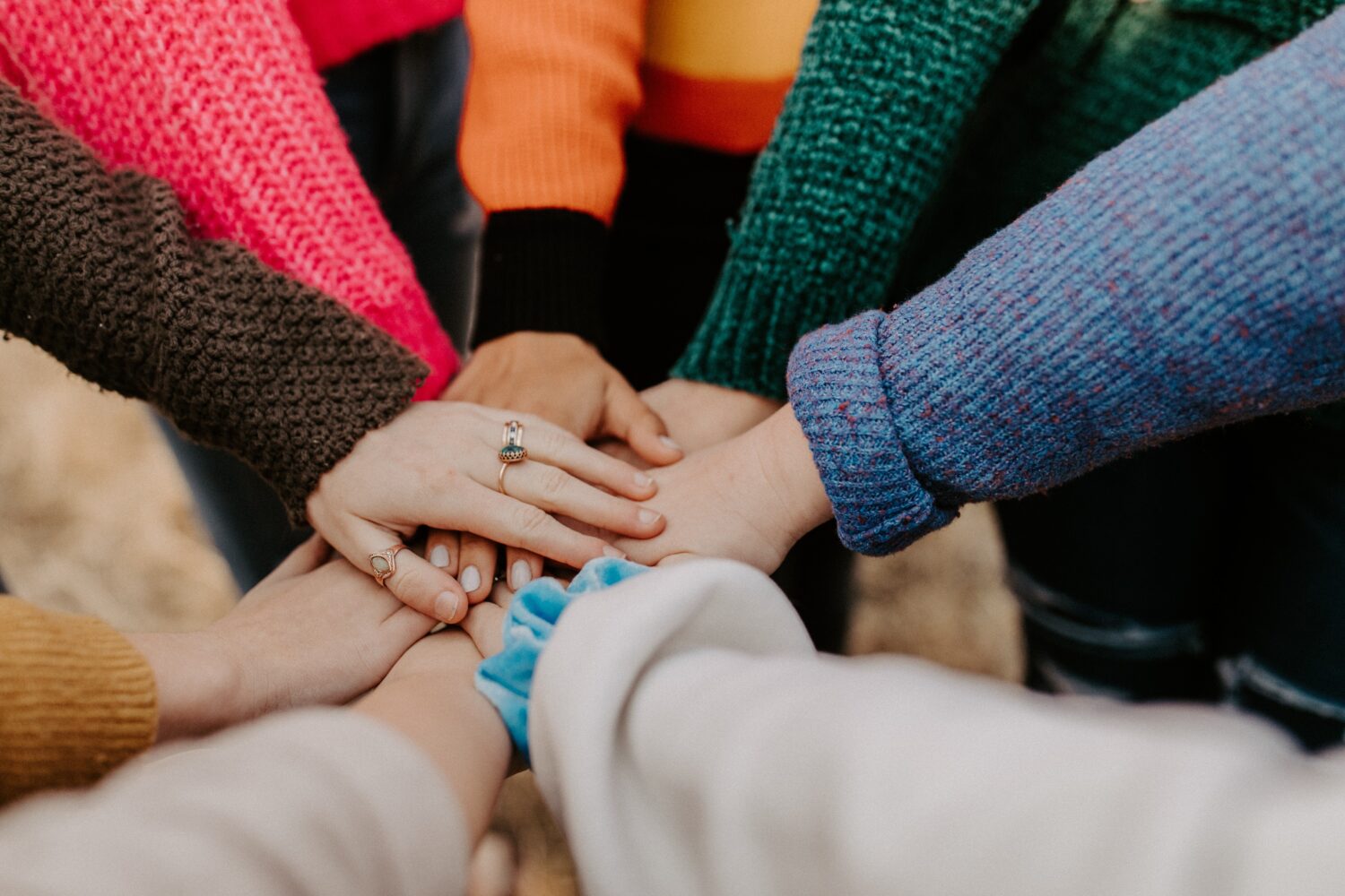 Eight people stacking their hands in a huddle